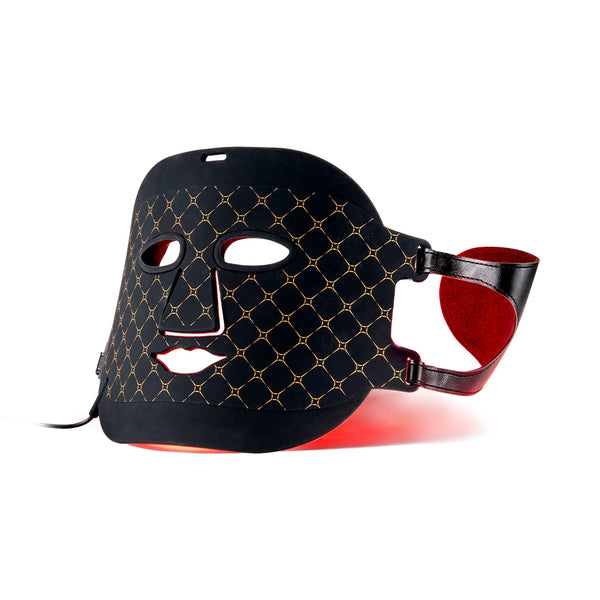 A black LED light therapy face mask with a gold geometric pattern, featuring a red interior lining and adjustable strap, shown on a white background.